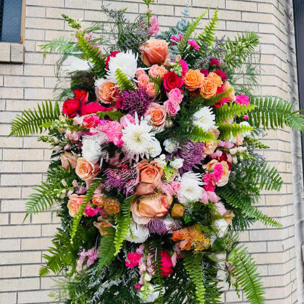 Large standing floral spray with pink, peach, white, and purple flowers