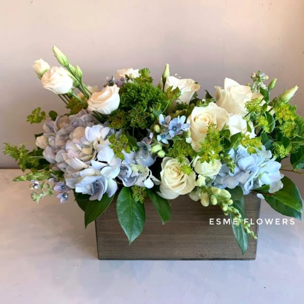Cream roses and blue hydrangeas in a wooden box