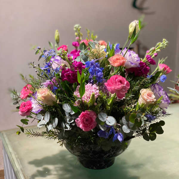 Mixed pink, purple, and blue flowers arranged in a black vase