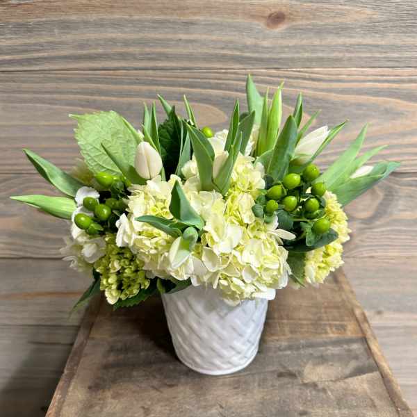 White and green floral arrangement in a white textured vase