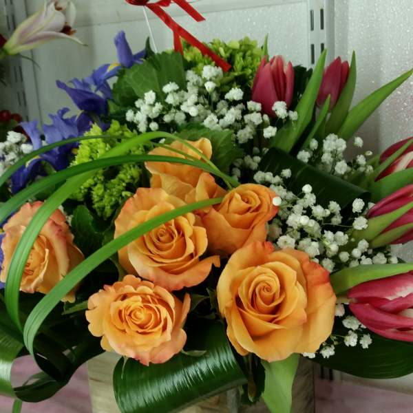 Orange roses and pink tulips in a wooden box with white filler flowers