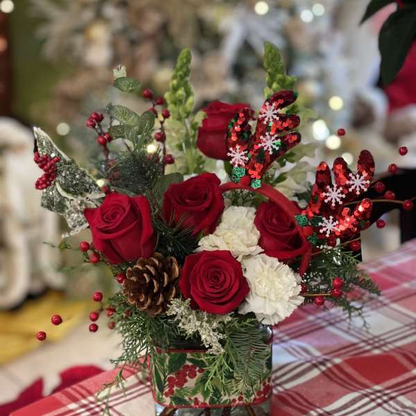 Red roses and white carnations in a glass vase with holiday decorations