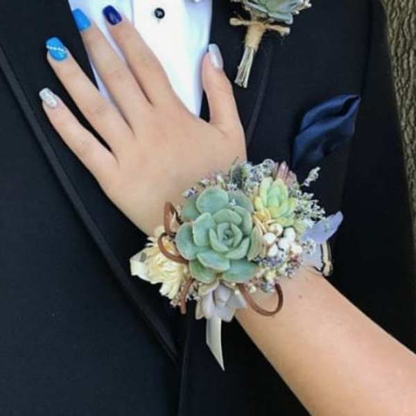 Hand corsage with pale succulents and small white flowers on a wrist ribbon
