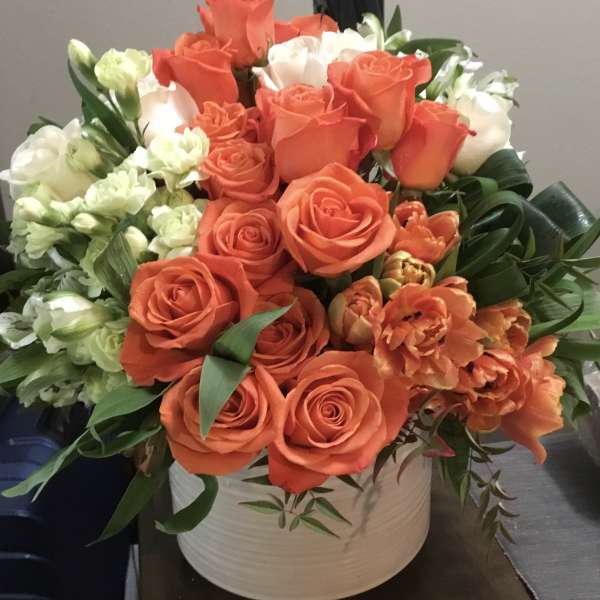 Orange and white roses with orange tulips in a white vase