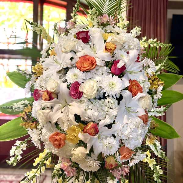 Large standing floral spray with white lilies and mixed roses