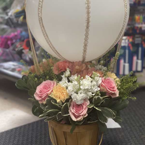 Basket arrangement with pink roses and white flowers beneath a large white balloon