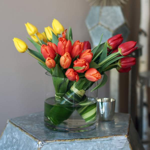 Bouquet of red, orange, and yellow tulips in a clear glass vase