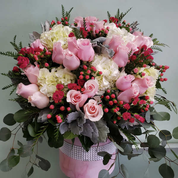 Pink roses and white hydrangeas in a pink hatbox arrangement
