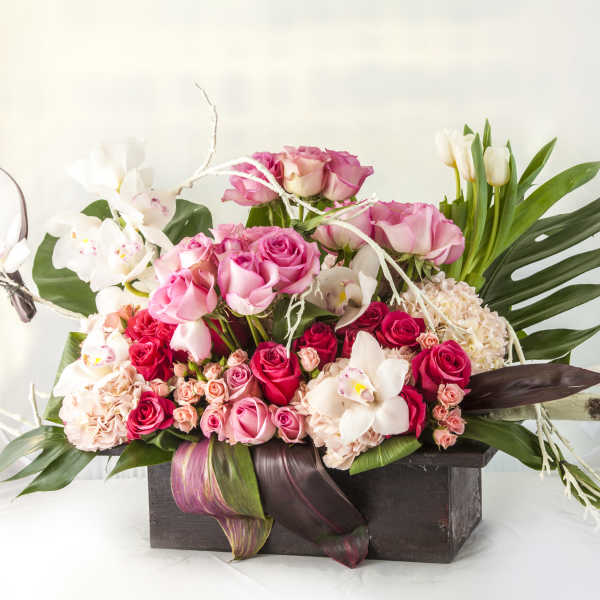 Pink roses and white orchids arranged in a dark wooden box