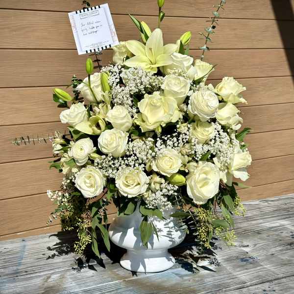 White rose and lily arrangement in a white pedestal vase