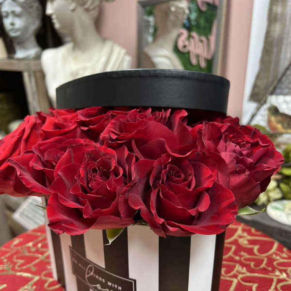 Red roses arranged in a black-and-white striped hat box