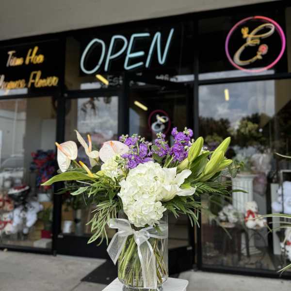 Bouquet of white lilies, hydrangeas, and purple flowers in a glass vase