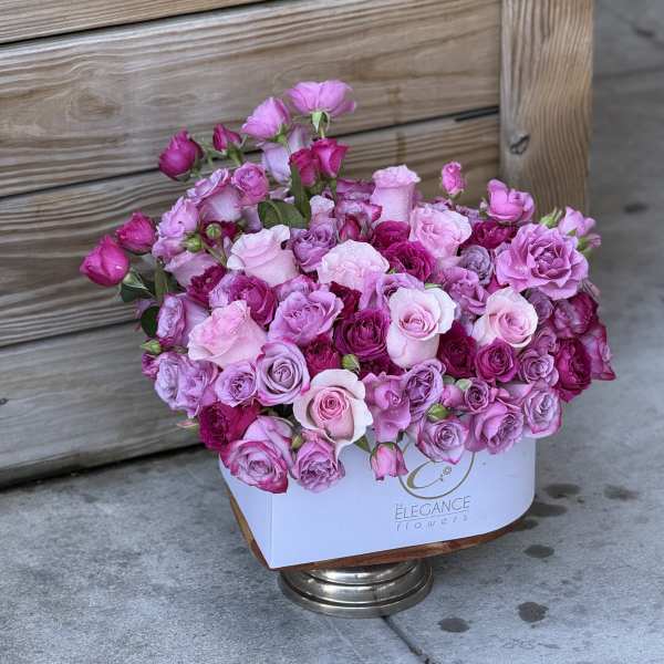 Pink and lavender rose bouquet in a white box on a metal stand