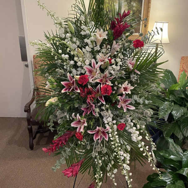 Large standing floral spray with pink lilies and white flowers on an easel