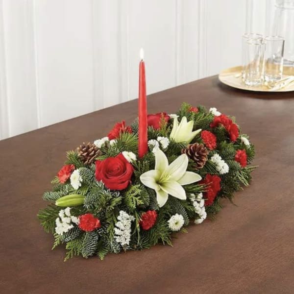 Holiday centerpiece with red roses, white lilies, and a red taper candle