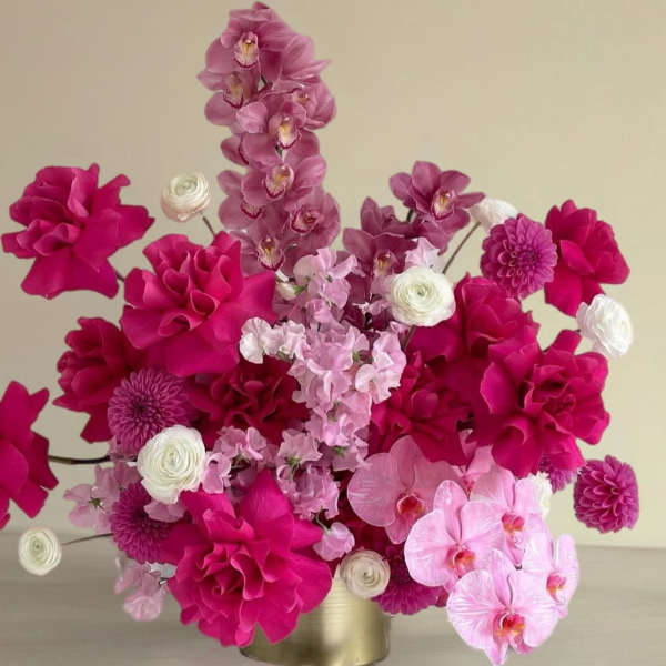 Pink floral arrangement with orchids, dahlias, and ranunculus in a gold vase