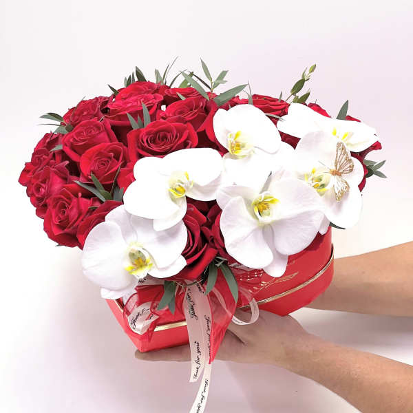 Red roses and white orchids arranged in a heart-shaped box