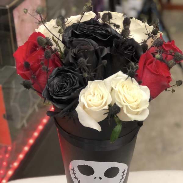 Bouquet of red, black, and white roses in a black cone with a skull face