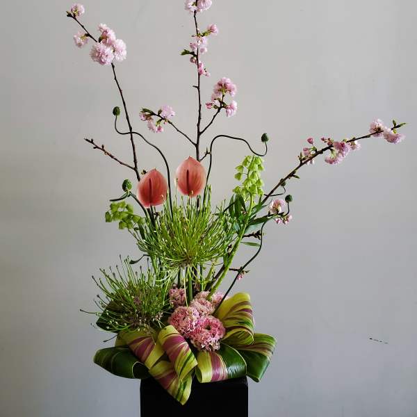Tall floral arrangement with pink blossoms and two pink anthuriums