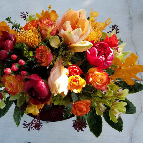 Bright mixed bouquet with orange, red, and yellow flowers in a low container