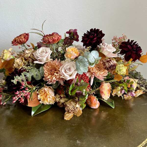 Low floral arrangement with roses, chrysanthemums, and dark dahlias