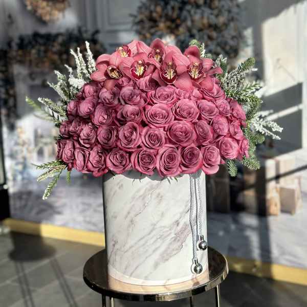 Pink roses and orchids arranged in a marble-patterned hat box