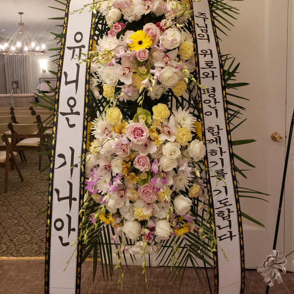 Tall standing floral wreath with white and pink flowers and Korean condolence ribbons