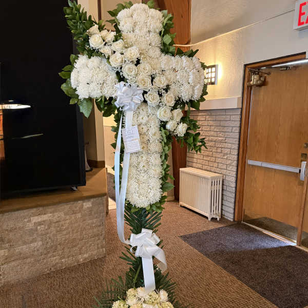 Tall white floral standing cross with ribbon bows