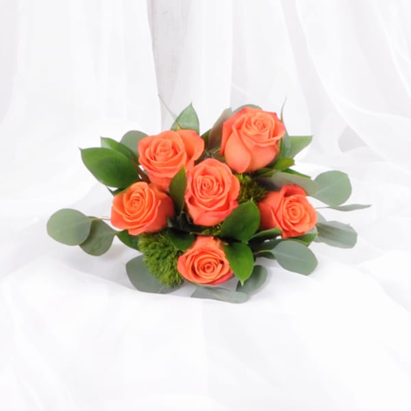 Cluster of bright orange roses arranged into a small bouquet on white fabric