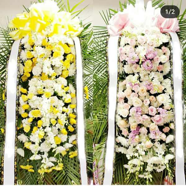 Two tall floral standing sprays with yellow and pink-white roses and ribbons