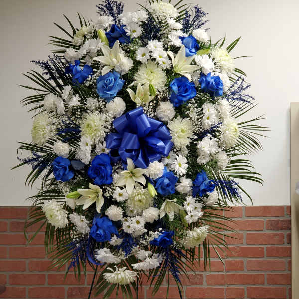 Large blue and white standing spray with roses, lilies, and mums on an easel.