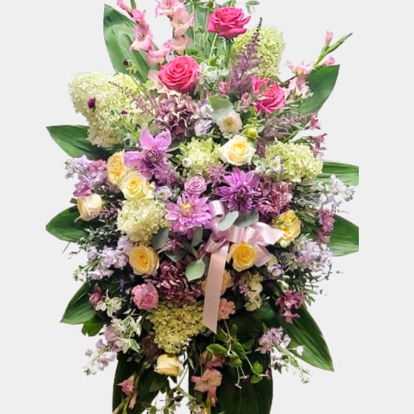 Tall standing floral spray with pink and yellow flowers and a ribbon