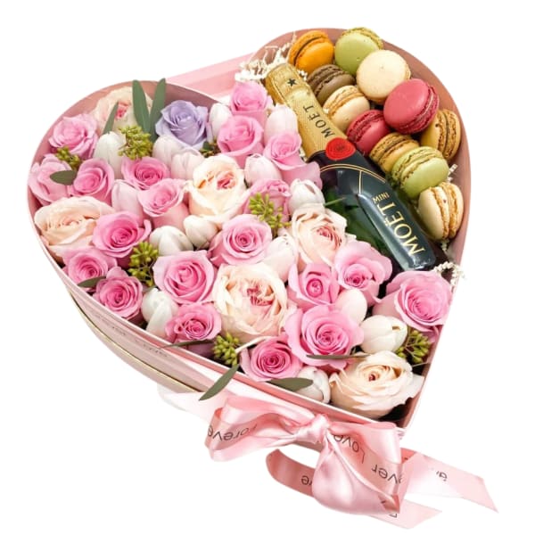 Heart-shaped box of pink roses and macarons with a ribbon bow