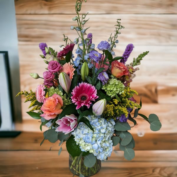 Mixed bouquet in a glass vase with pink, purple, blue, and orange flowers