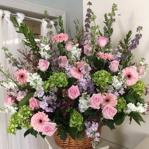 Large basket arrangement of pink roses, gerbera daisies, and purple flowers
