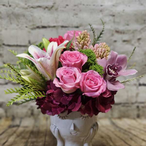 Pink roses and lilies arranged in a white ceramic vase