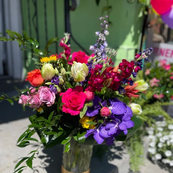 Colorful mixed bouquet in a glass vase with roses and orchids