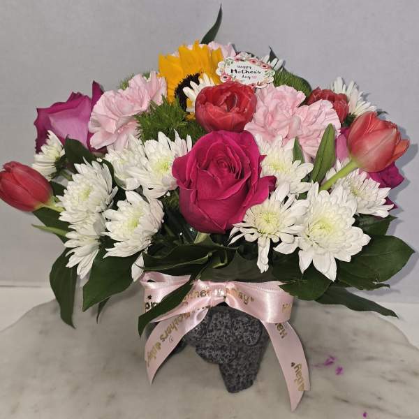 Mixed bouquet of roses, tulips, carnations, and white daisies in a vase