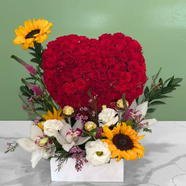 Heart-shaped red rose arrangement with sunflowers and white flowers in a white box