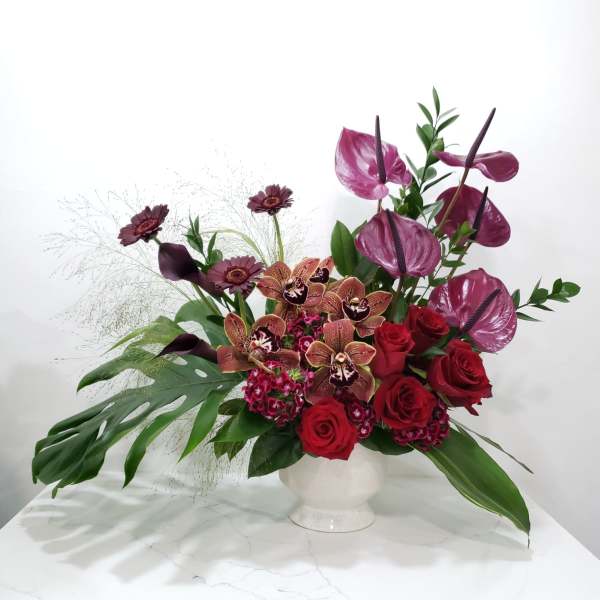 Red roses and purple orchids in a white vase