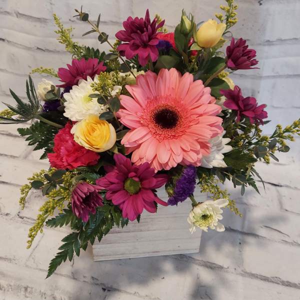 Mixed bouquet in a white wooden box with pink, yellow, and white flowers