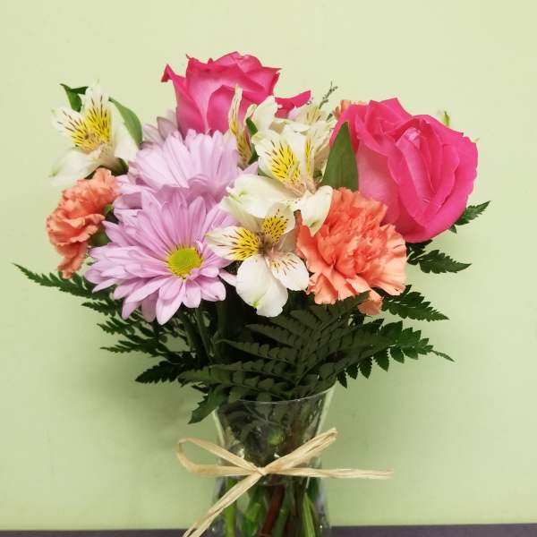 Bouquet of pink roses, lavender daisies, and white alstroemeria in a glass vase