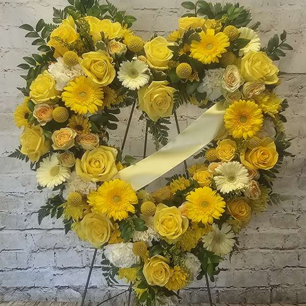 Yellow floral heart wreath on a stand with a pale ribbon