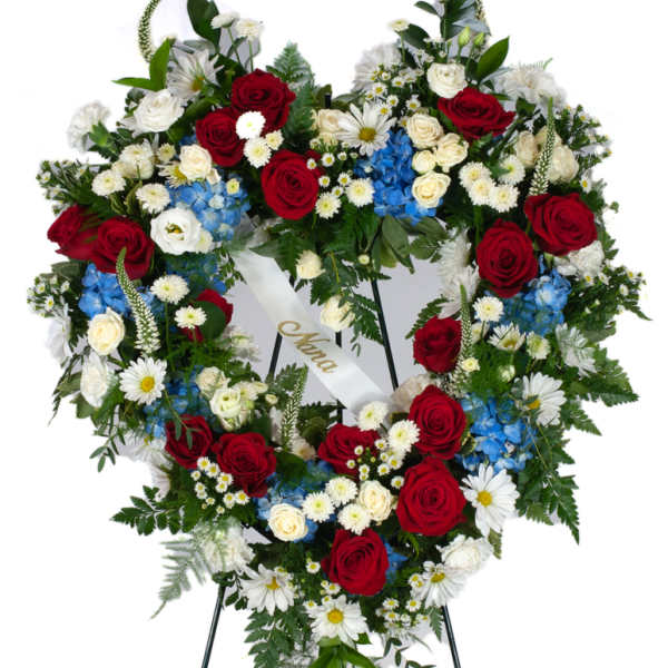 Heart-shaped standing wreath of red, white, and blue flowers on an easel