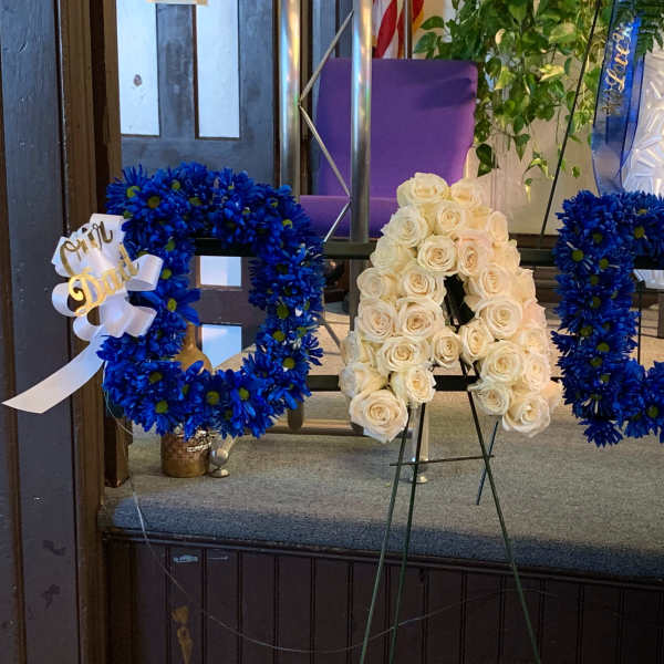 Blue floral letter wreaths and a white rose letter arrangement on stands