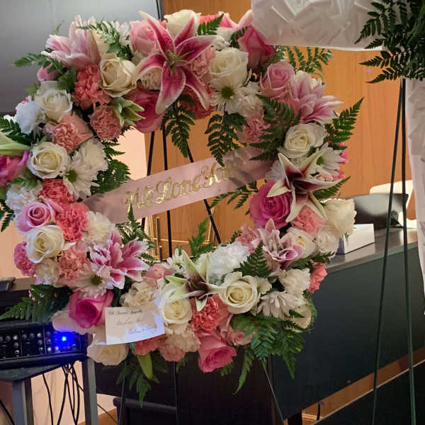 Heart-shaped floral wreath with pink and white flowers and a ribbon