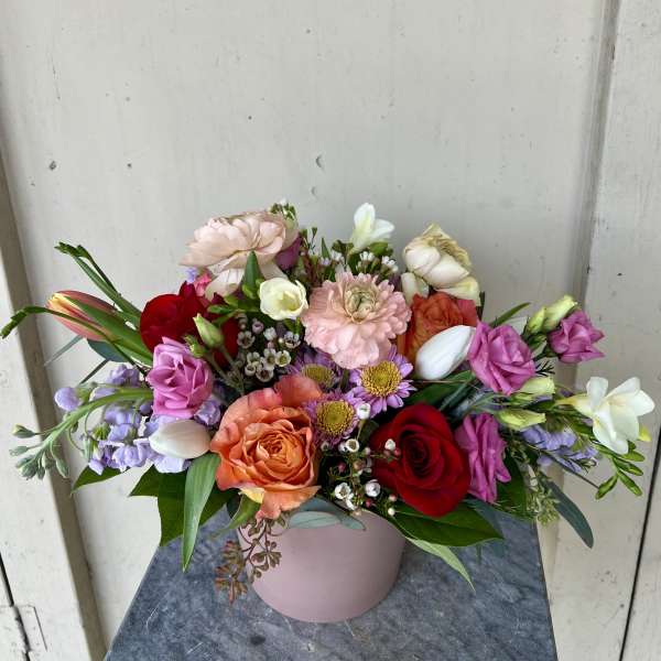 Mixed bouquet of roses, tulips, and daisies in a pink vase