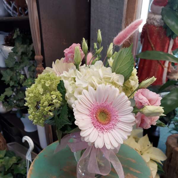 Pink gerbera bouquet with white hydrangea and ribbon in a glass vase