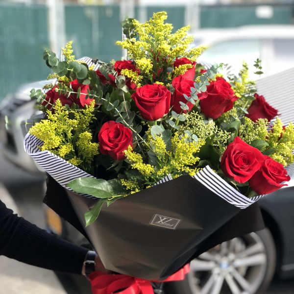 Bouquet of red roses with yellow filler flowers and black wrapping