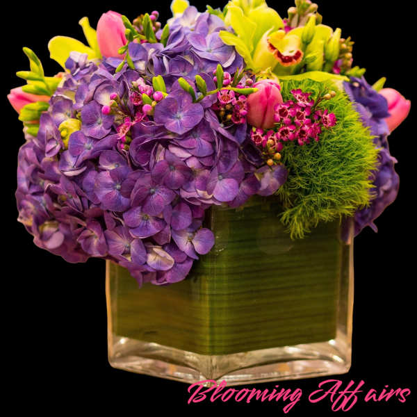 Purple hydrangeas and pink tulips in a square glass vase